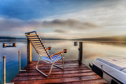 Chair sitting at the end of a dock in very early morning summer light