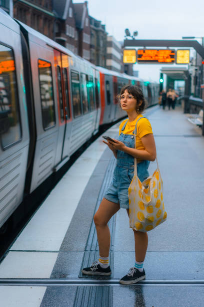 istock Woman waiting for the train on a subway station and using smartphone 1494659907
