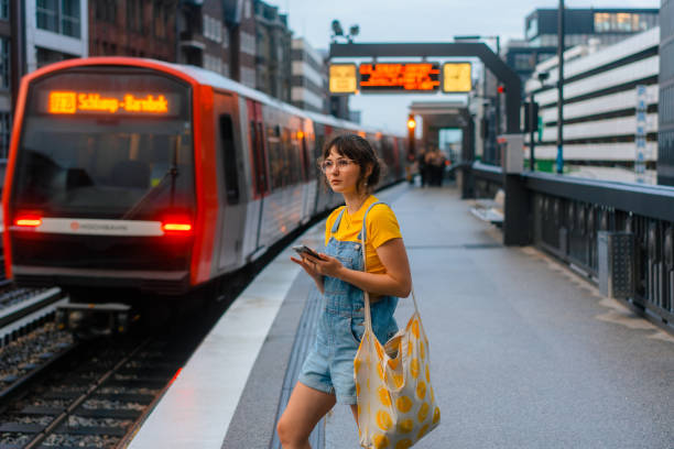 地下鉄の駅で電車を待っていてスマートフォンを使う女性 - subway station subway train underground hamburg germany ストックフォトと画像