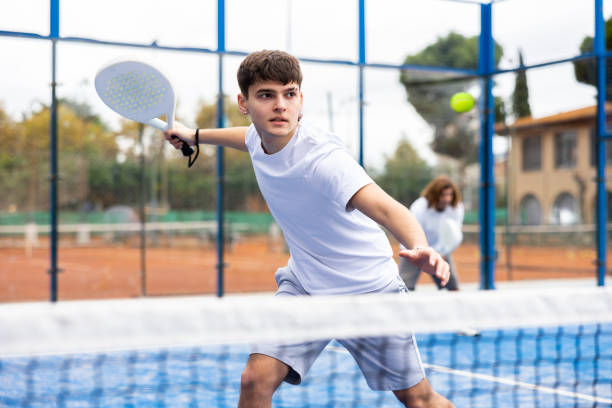 istock Sporty young guy playing padel on open court 1494660391