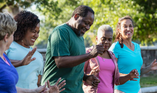 Mature and senior adults in dance exercise class in park A multiracial group of five adults in a dance exercise class at the park, standing in a row, side by side. The main focus is on the only man in the group of women. He is middle, a mature African-American man in his 50s. native american exercising men people stock pictures, royalty-free photos & images
