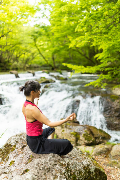istock A woman meditating by a waterfall 1494669359