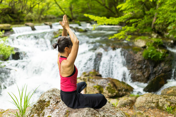 istock A woman meditating by a waterfall 1494669362