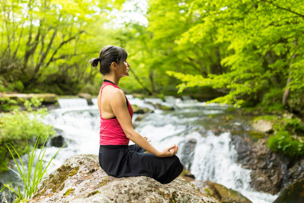 A woman meditating by a waterfall stock photo