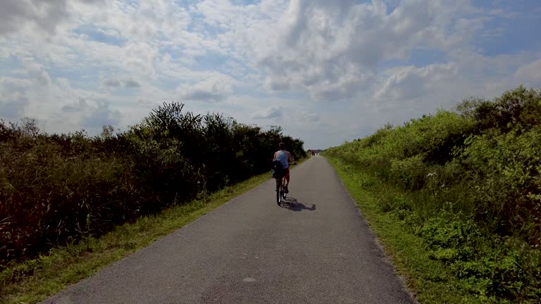 Following Woman Riding Bicycle On Narrow Path