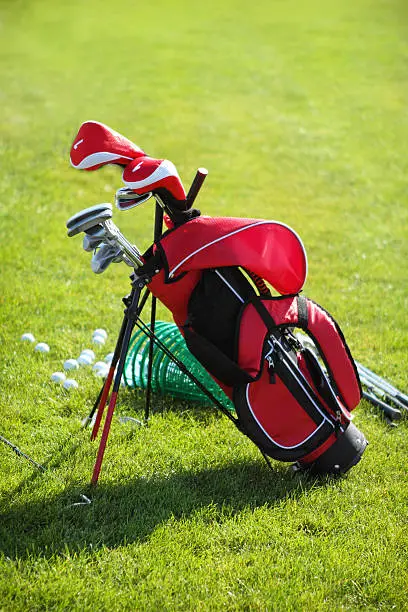 Golf clubs in golfbag and golf balls green grass background
