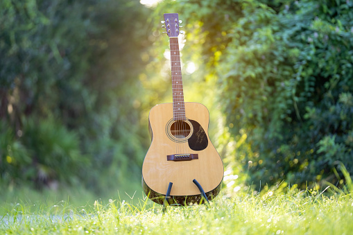Acoustic guitar outdoors on greenery background. Concept of calm music.