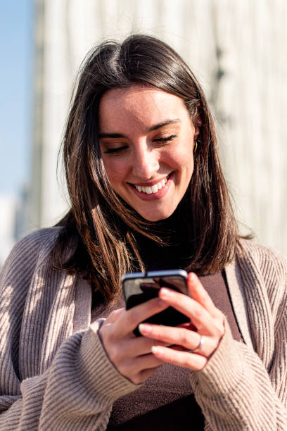 istock woman smiling happy while texting on her phone 1494677132