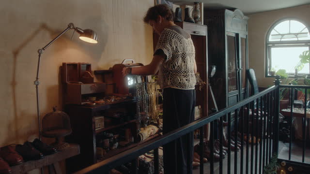 Woman Walking Upstairs in Vintage Store and Taking Items for Sale