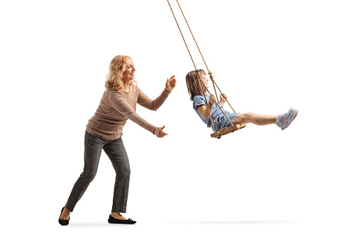Woman pushing a little girl on a swing isolated on white background
