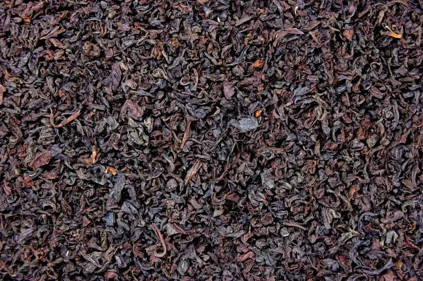 Dark black loose Indian Assam orange pekoe OP tea leaf texture, English Breakfast Ceylon blend flat lay pattern, large detailed horizontal isolated macro closeup