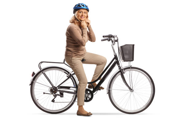 Mature woman with a bicycle putting on a helmet stock photo