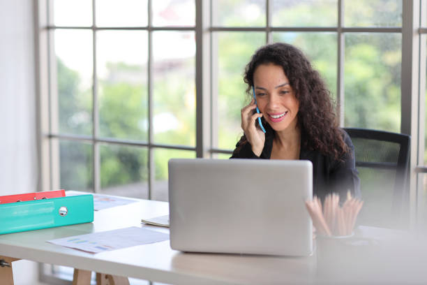 istock Attractive professional latin female employee worker sitting, using laptop computer with paperwork at home workplace. Businesswoman talking on smart mobile phone and communicate with client. 1494683727