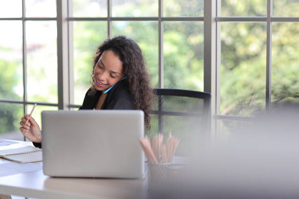 istock Attractive professional latin female employee worker sitting, using laptop computer with paperwork at home workplace. Businesswoman talking on smart mobile phone and communicate with client. 1494683734