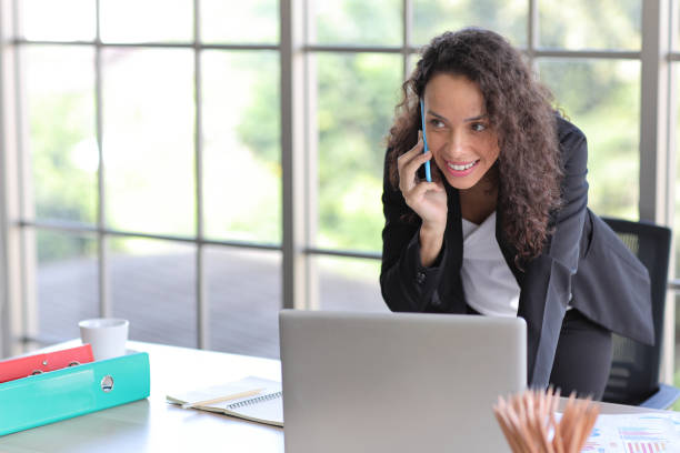 istock Attractive professional latin female employee worker sitting, using laptop computer with paperwork at home workplace. Businesswoman talking on smart mobile phone and communicate with client. 1494683797