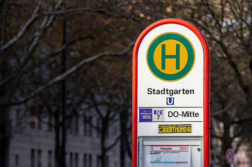 Picture of a typical german and bus stop roadsign, indicating a haltestelle, or bushaltestelle, with it H and a iconic yellow and green colors.