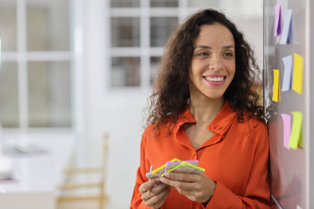 istock Smart and active latin woman standing and holding different colored sheets of note papers, ready for message on refrigerator in kitchen. Anywhere can work, lifestyle with technology concept 1494689243