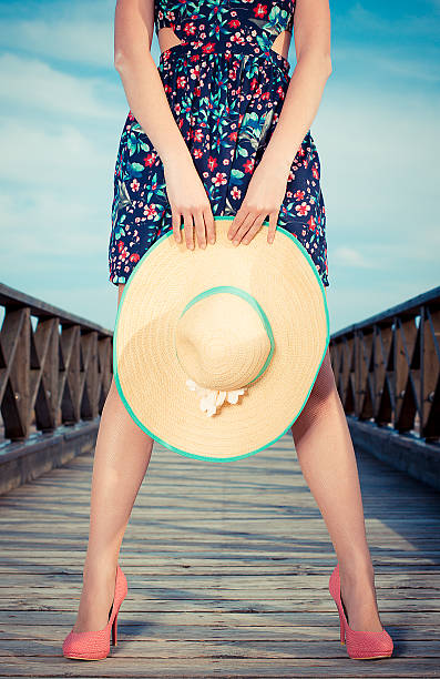 Girl standing on a bridge holding hat stock photo
