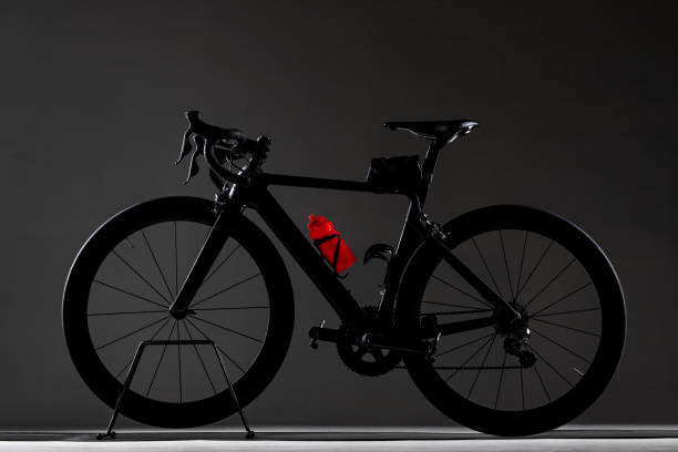 Black roadbike with red water bottle on dark studio background. Generic design.