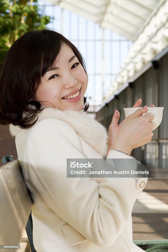 Японская девушка сидит на скамейке и пить кофе - Стоковые фото 18-19 лет роялти-фри