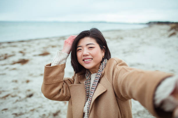 istock Young Asian woman taking a selfie on a beach 1494695401