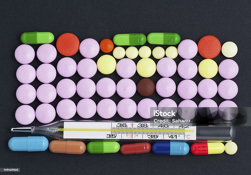 Pills and thermometer Pills and thermometer over dark background Antibiotic Stock Photo