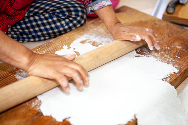 Housewife preparing rotis (chapatis) for dinner. With a messy counter to work with.