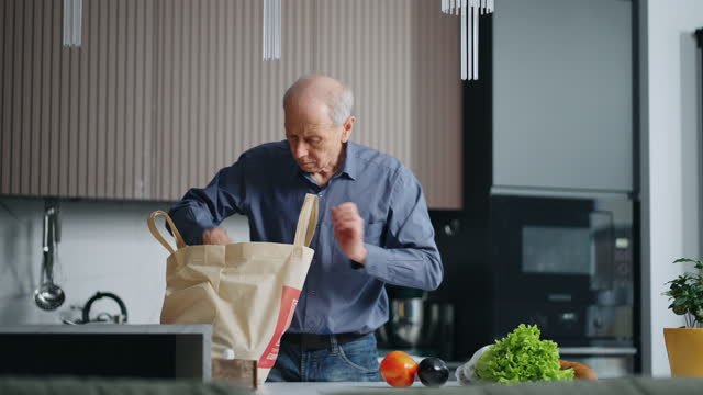 Single Old Man Unpacking Purchases From Grocery, Putting Eco Fabric Bag With Food On Kitchen Table