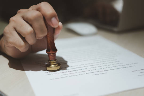 istock Hand holding rubber stamp on document paper.Approval job application. Legal Contract Work Paper and public notary clerk certificate and agreements on desk. 1494707949