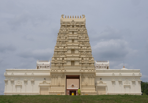 Exterior of Hindu Temple in Austin, Texas, on cloudy day with woman in lime green sari entering the temple.