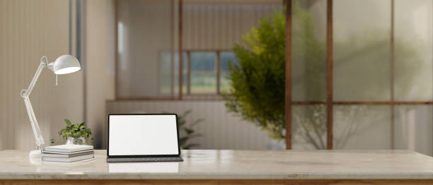 istock A tablet white screen mockup on a tabletop over blurred background of a minimal room. 1494721499