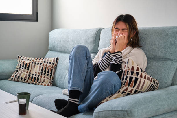 istock Sick taiwanese man blowing his nose with a tissue on a sofa. 1494723327