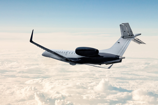 Modern luxury private jet flies in the air above the clouds
