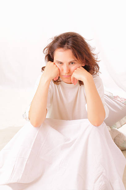 Angry young woman sitting in bed stock photo