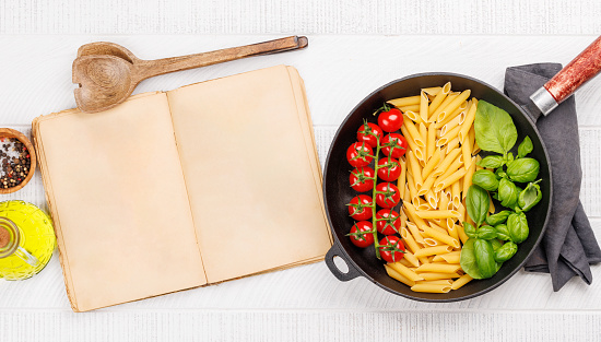 A vibrant representation of the Italian flag made with pasta, basil, and tomatoes, beautifully presented in a frying pan, and cookbook page for your recipe. Flat lay with copy space