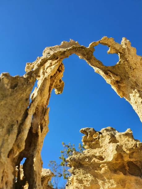istock Natural rock formation featuring an archway against a bright blue sky. 1494736479