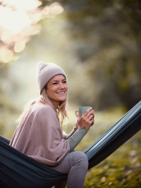 istock Happy woman day dreaming while drinking coffee in hammock at the park. 1494740943