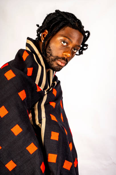 istock Young African man wrapped in distinctive black and red checked fabric moves. 1494741074