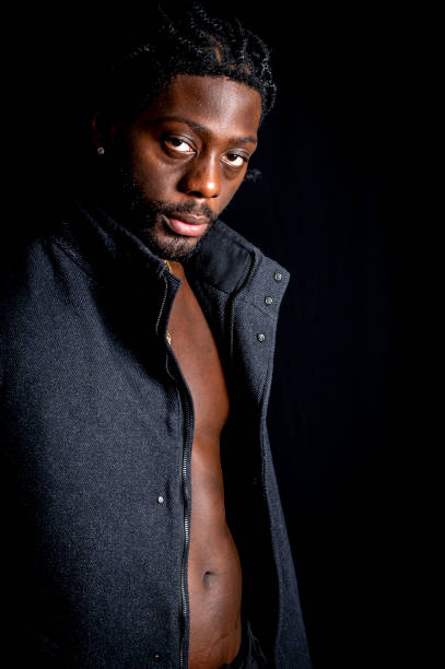 Young African man in a black coat looks sideways before going out.