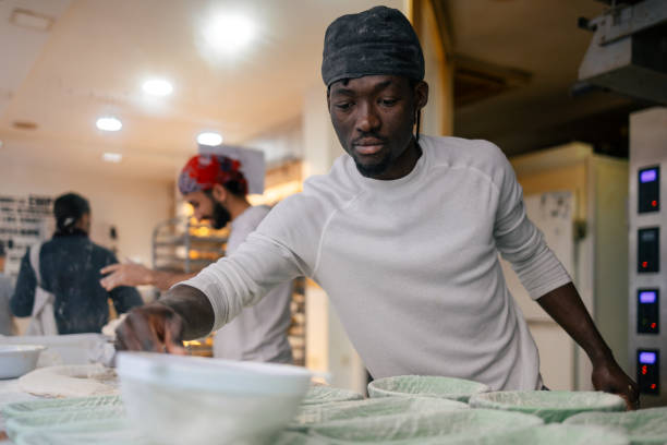 istock Black baker pouring flour with a sifter 1494754681