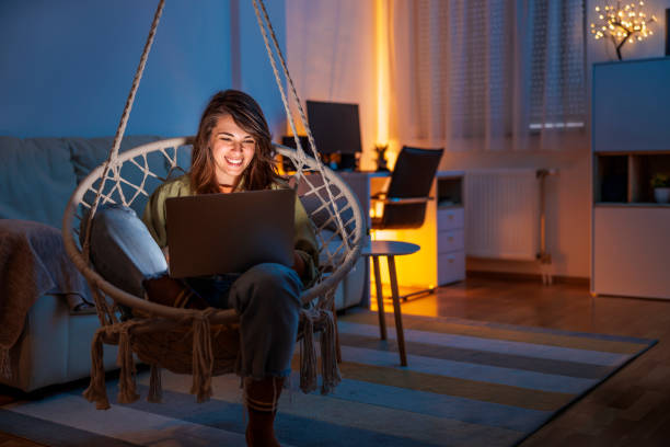Woman using laptop computer while relaxing at home late at night stock photo