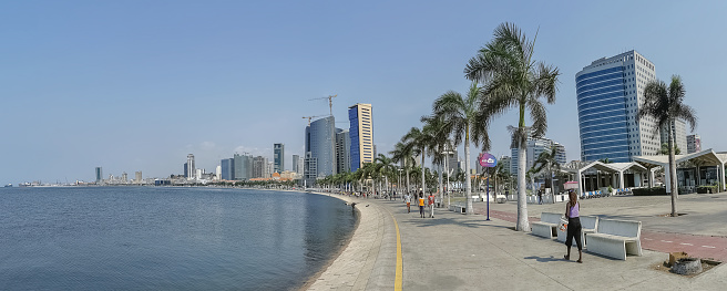 Luanda Angola - 10 09 2022: Panoramic view at the Luanda bay and Luanda marginal, pedestrian pathway with tropical palm trees, downtown lifestyle, Cabo Island, Port of Luanda and modern skyscrapers