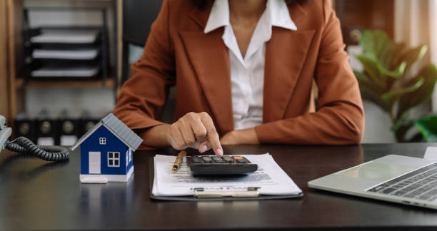 home loan officer uses a calculator with a house plan. - sale stok fotoğraflar ve resimler