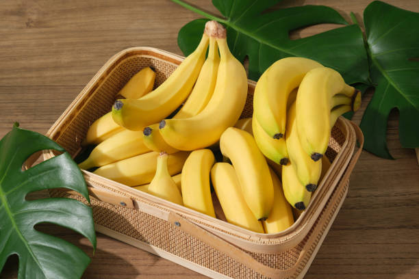 BANANA CONCEPT Bananas are arranged inside a bamboo basket decorated with some fresh green leaves. Banana (Musaceae) will protect the body from damage caused by the oxidation of free radicals banana stock pictures, royalty-free photos & images