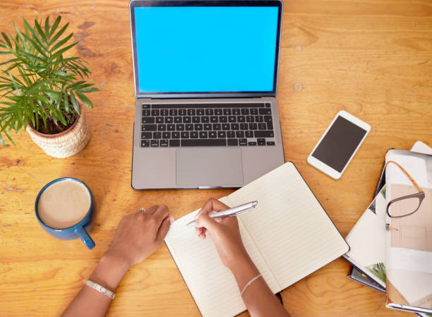 istock Top view, mockup and laptop with green screen, hands and planning for project, deadline and journal. Female, employee and device with communication, writing and notes for idea, branding and notebook 1494764790