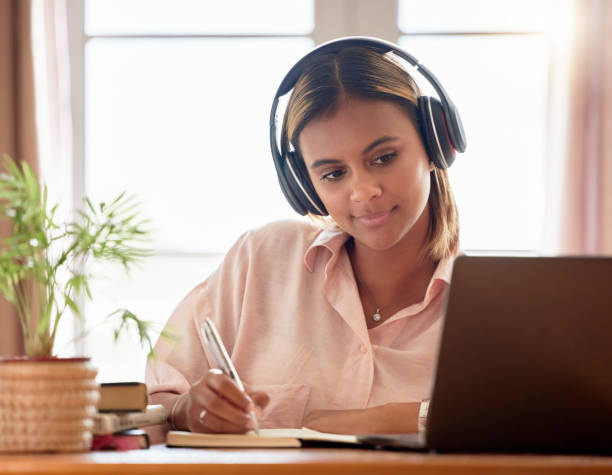 istock Woman, student with laptop and headphones, writing notes in notebook, education and elearning with study notes. Mexican female, internet with wifi and tech, online class with webinar and studying 1494764817