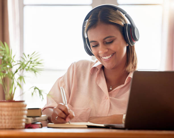istock Woman, student with laptop and headphone, writing notes in notebook, education and study elearning course. Mexican female smile, internet and technology, online class with webinar and studying 1494764818