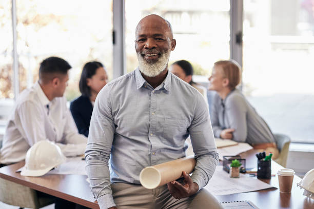 l'uomo nero, l'architetto e il ritratto sorridono con il progetto nella pianificazione del team per la costruzione o la costruzione in ufficio. senior leader africano ceo appaltatore o ingegnere con planimetria in architettura - business ceo building activity business person foto e immagini stock