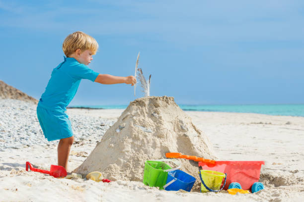 istock Boy building sand castle putting feather on top of the tower 1494766726