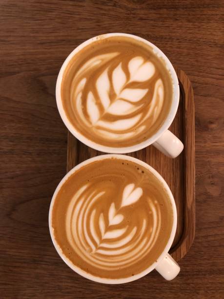 istock Two cappuccino coffee cups with the heart shape closeup top view, rustic wooden background. 1494767013